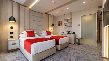 A modern hotel room with two beds, a desk, and a wardrobe.