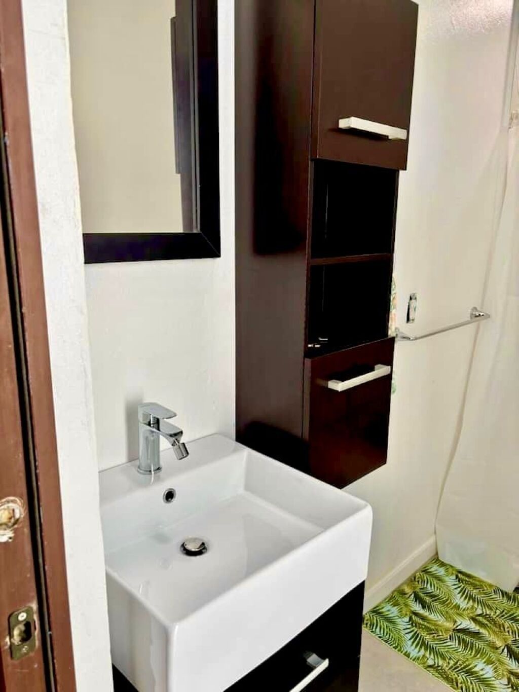 A bathroom with a white sink, a mirror, and a dark wooden cabinet.