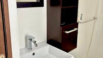 A bathroom with a white sink, a mirror, and a dark wooden cabinet.