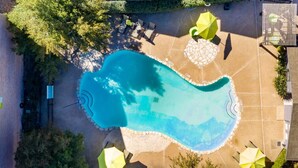 An aerial view of a swimming pool surrounded by a patio area with umbrellas and seating. - Sleepover | Peaceful 1BD/1BA + Gym - Austin TX (Austin)