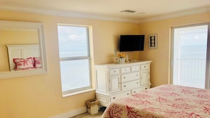 Ein Schlafzimmer mit Bett, Kommode, Fernseher und Fenster mit Meerblick.