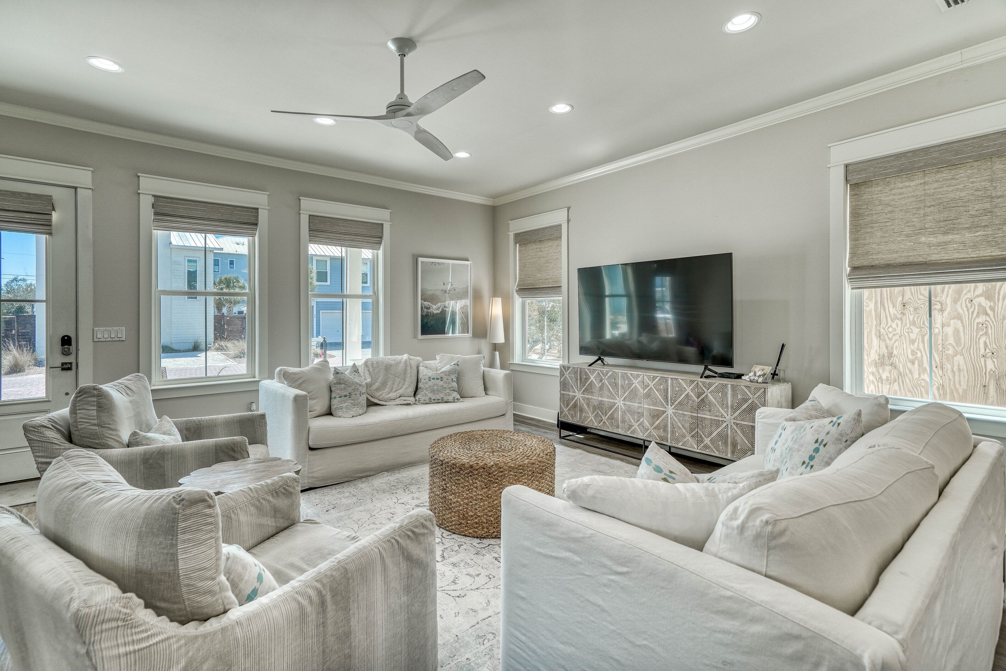 A spacious living room with a large flat-screen TV, comfortable seating, and a ceiling fan.