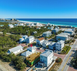 Vista aérea de una zona residencial costera con casas, una playa y un cielo azul despejado.