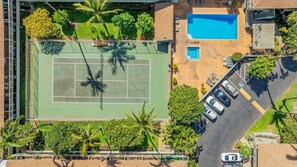 Vista aérea de una propiedad con cancha de tenis, piscina y zona de estacionamiento.