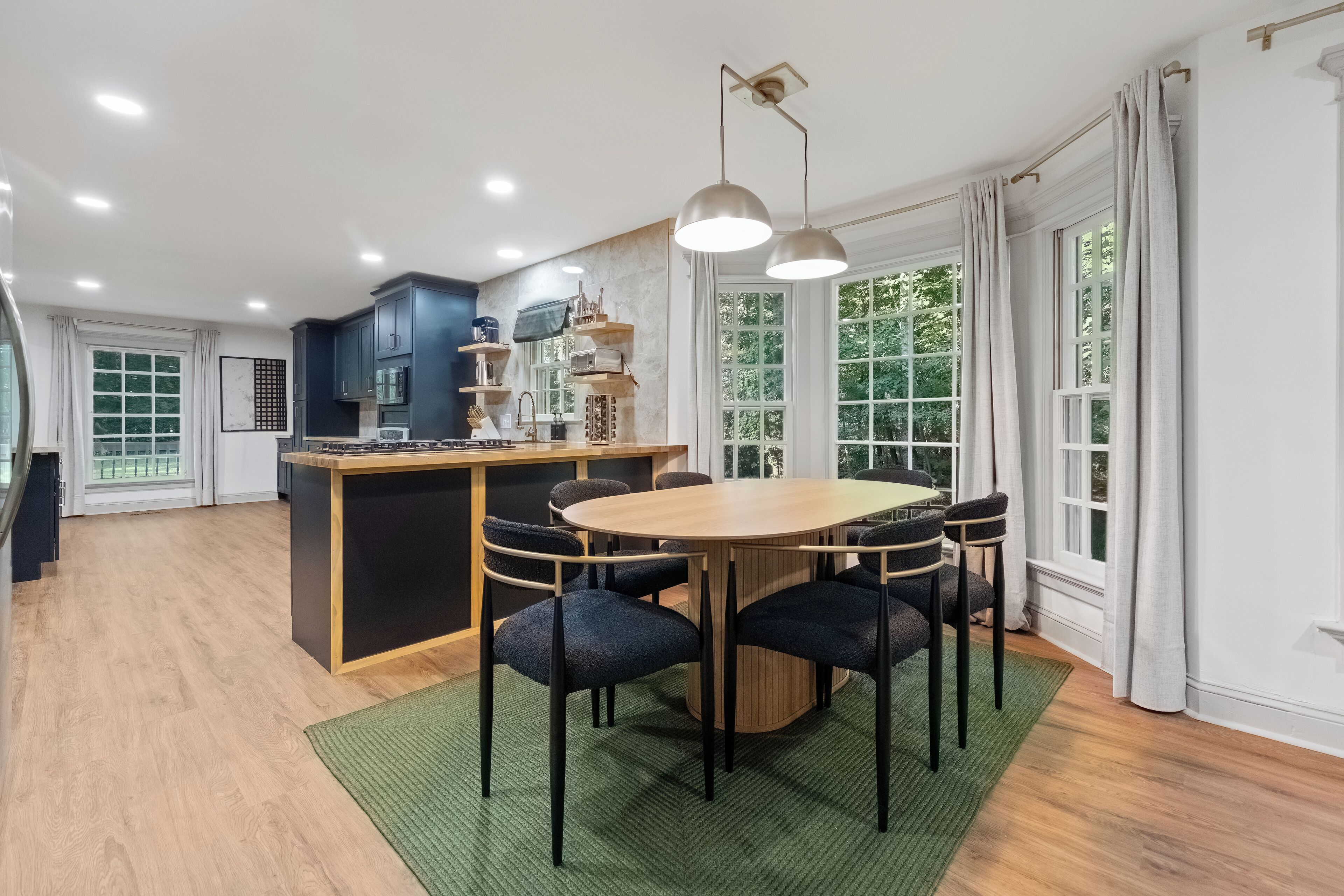 A modern kitchen with dark cabinets, a central island, and pendant lighting.