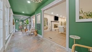 A spacious hallway with a green wall, a fireplace, and a dining area.