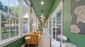 A corridor with large windows, a sofa, and chairs.