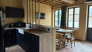 A kitchen with a central island, black cabinets, and a wooden ceiling.