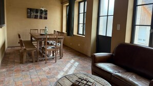 A dining area with a wooden table and chairs, a leather couch, and a round coffee table.