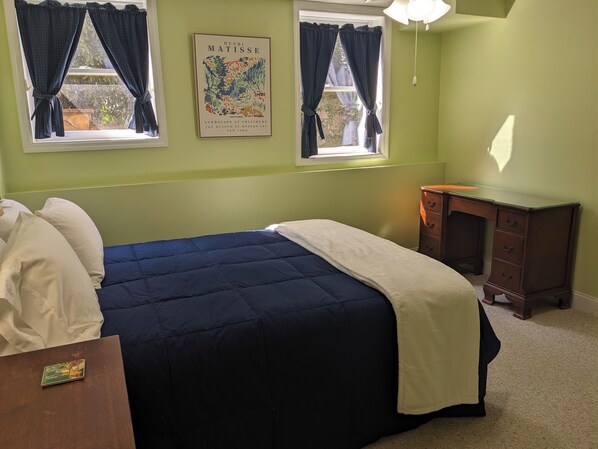 A bedroom with a bed, two windows with curtains, a nightstand, a dresser, and a poster on the wall. - Delightful Five Points 2-bedroom apartment - walk to UGA stadiums! (Athens)