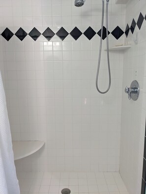 A small, white-tiled shower room with a handheld showerhead and a wall-mounted faucet. - Delightful Five Points 2-bedroom apartment - walk to UGA stadiums! (Athens)