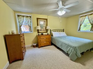 A bedroom with a bed, dresser, nightstand, and a ceiling fan.