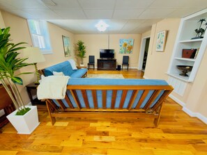 Ein Zimmer mit einem Bett, einem Fernseher, einer Pflanze und einem Regal mit Dekoration.