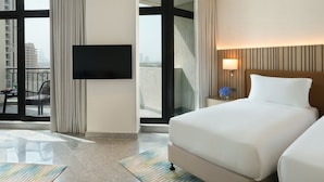 Une chambre d’hôtel dotée d’un grand lit, d’une télévision à écran plat, d’un balcon offrant une vue sur la ville et d’un design moderne.