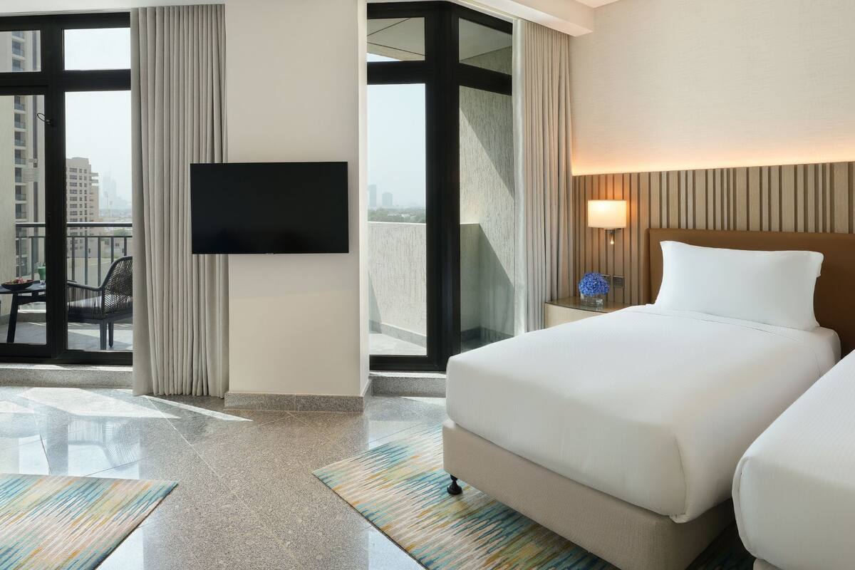 Une chambre d’hôtel dotée d’un grand lit, d’une télévision à écran plat, d’un balcon offrant une vue sur la ville et d’un design moderne.