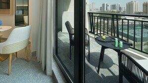 Una habitación de hotel moderna con balcón, comedor y vistas al horizonte de la ciudad.