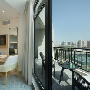 Une chambre d’hôtel moderne avec balcon, un coin repas et une vue sur le panorama urbain.