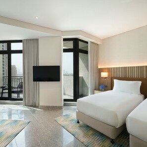 Une chambre d’hôtel dotée d’un grand lit, d’une télévision à écran plat, d’un balcon offrant une vue sur la ville et d’un design moderne.