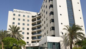 Un hotel moderno llamado Arabian Park, con una entrada destacada, varios pisos y un cielo despejado.