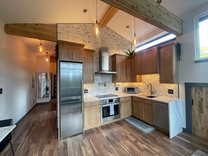 A modern kitchen with wooden cabinets, a stainless steel refrigerator, and a built-in oven. - “Blue Owl” - Tree House Views! Couples Getaway! (Idaho Springs)