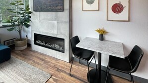Un salon moderne avec une cheminée, un coin repas avec une table en marbre et des œuvres d’art accrochées au mur.