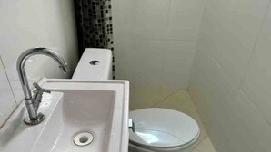 A bathroom with a white sink, a toilet, and a tiled wall. - Quarto individual em São Paulo ZN (São Paulo)
