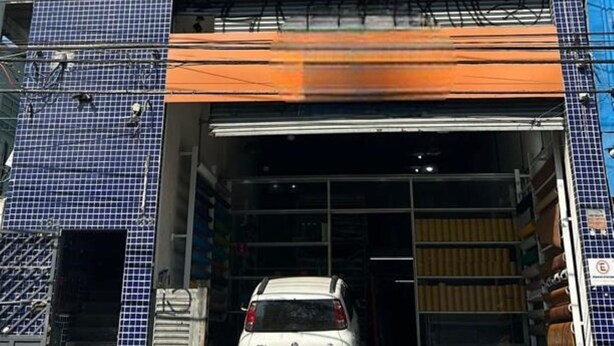 A multi-story building with a garage entrance, a parked car, and a staircase leading to the entrance. - Quarto individual em São Paulo ZN (São Paulo)