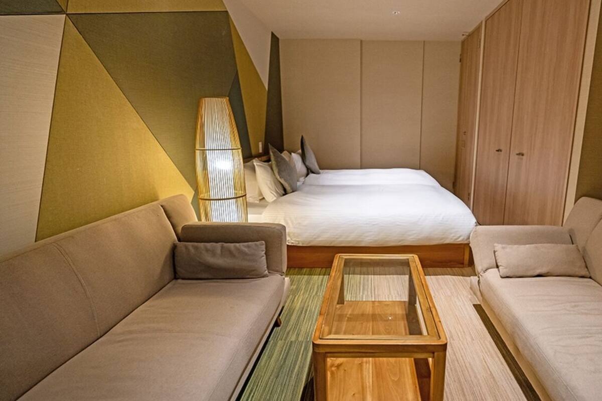 Ein Hotelzimmer mit einem Bett, zwei Sofas, einem Holztisch und einer Lampe.