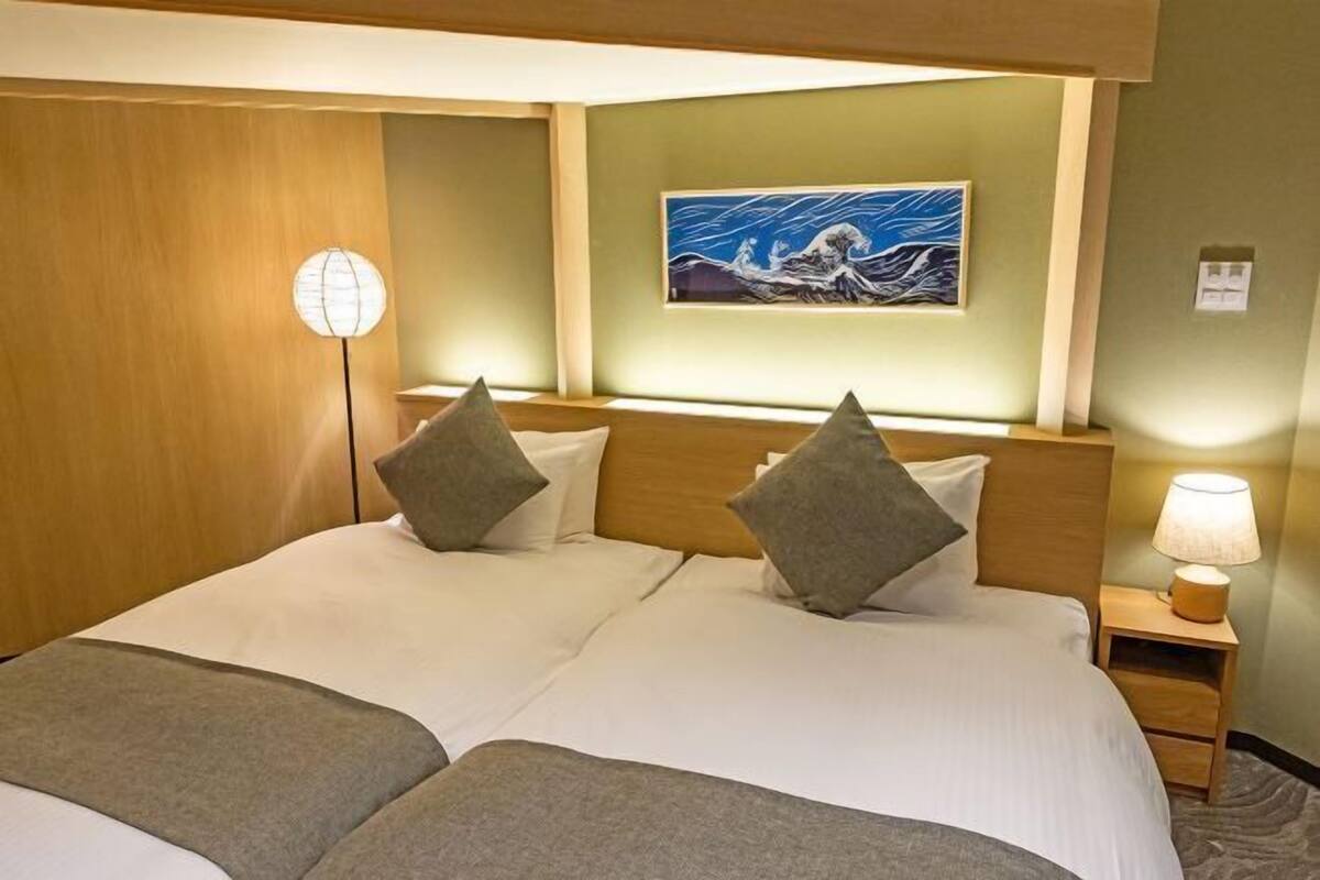 Ein Doppelbett mit zwei Kissen, ein Nachttisch mit Lampe und ein Bild an der Wand.