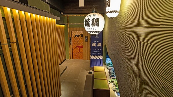A hallway with a traditional Japanese aesthetic, featuring a wooden slat wall and a sign for Asakusa Hotel. - Stay Sakura Tokyo Asakusa Yokozuna Hotel (Tokyo)