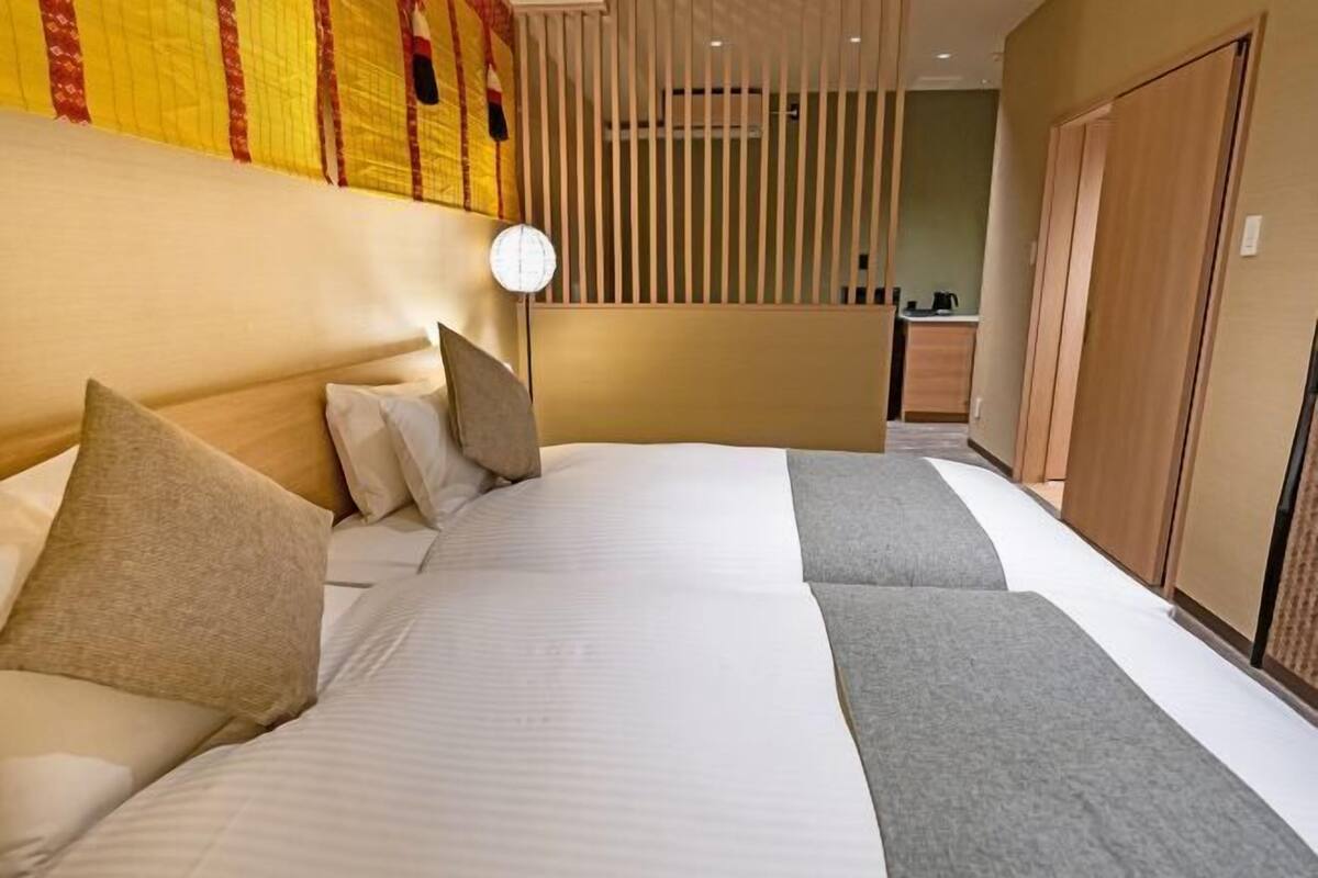 Ein Hotelzimmer mit einem großen Bett, einem Nachttisch, einer Uhr und einem Kleiderschrank.