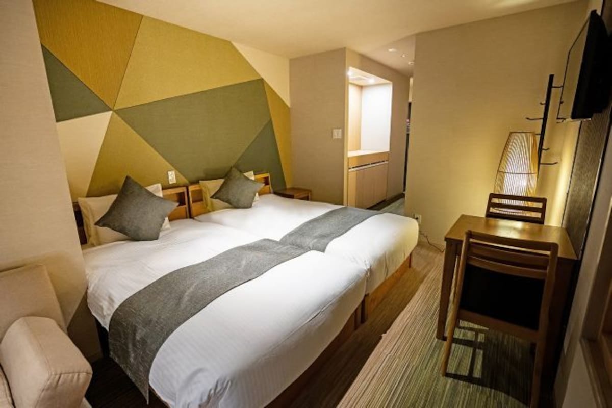 A hotel room with a large bed, a desk, a chair, and a television.