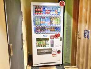 A vending machine with various drinks and snacks, a payment terminal, and a sign indicating a restroom. - Stay Sakura Tokyo Asakusa Yokozuna Hotel (Tokyo)