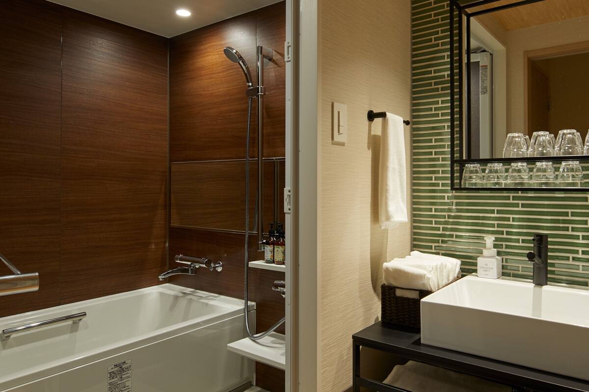 Ein modernes Badezimmer mit Badewanne, Dusche, Waschbecken und Spiegel.