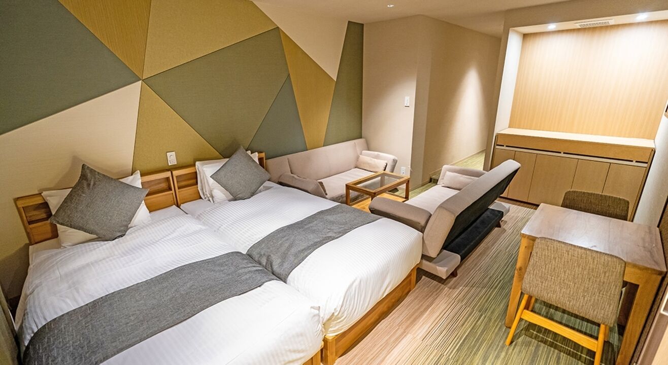 Une chambre d’hôtel avec deux lits, un canapé, une petite table et une chaise.