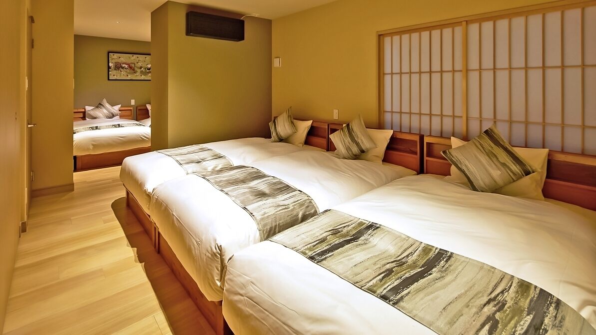 A hotel room with two beds, a wooden floor, a large window with a view, and a painting on the wall.