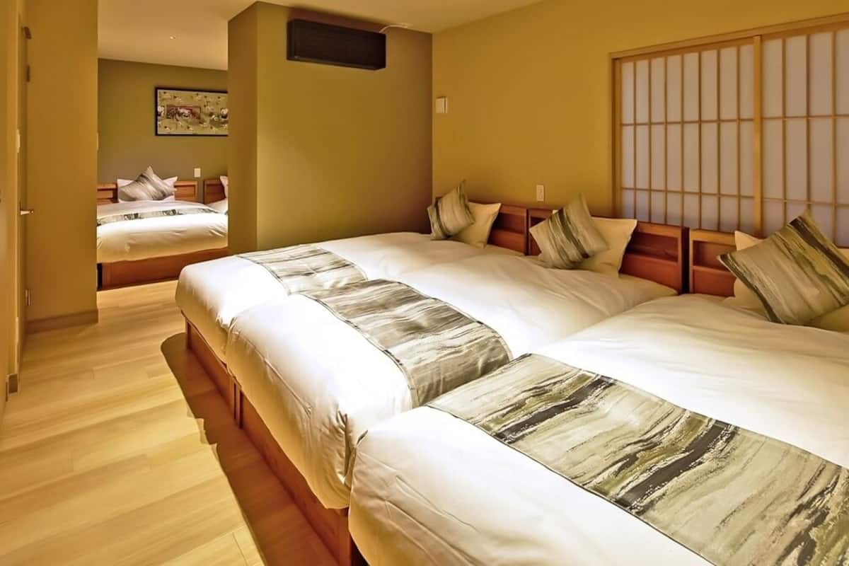 Ein Hotelzimmer mit zwei Betten, Holzboden, großem Fenster mit Aussicht und einem Gemälde an der Wand.