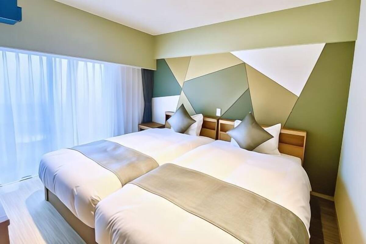 Ein Doppelbett mit Kopfteil, ein Nachttisch und ein Fenster mit Vorhängen.