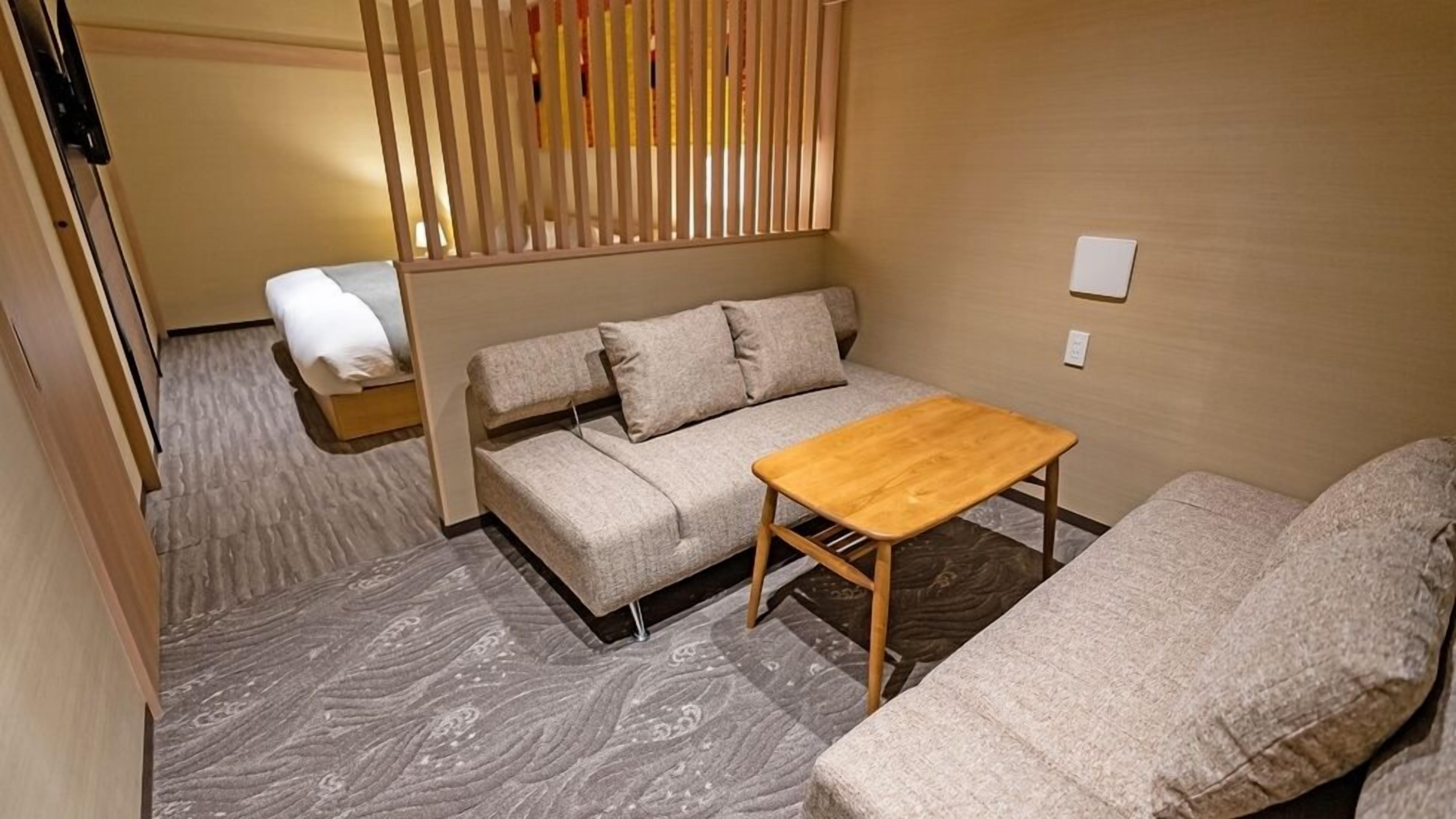 Une pièce de taille modeste, comprenant un canapé, une petite table en bois et un lit.