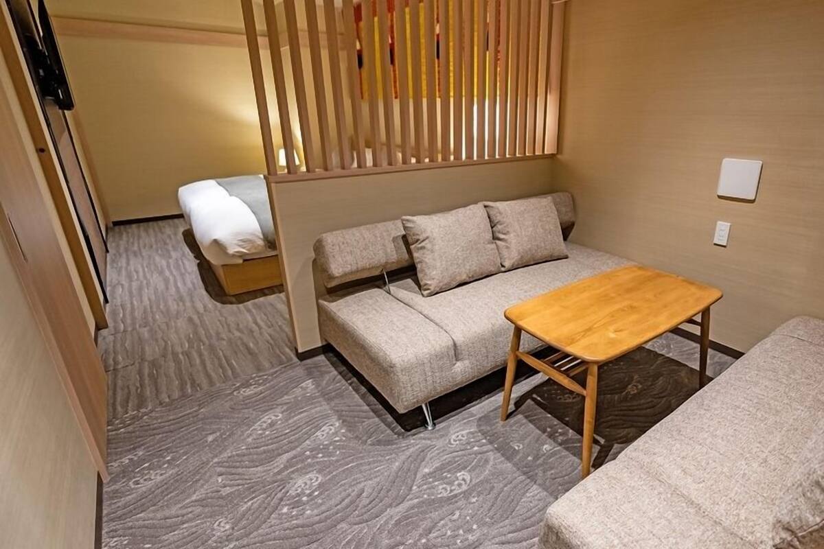 Ein gemütlicher Raum mit einer Couch, einem kleinen Holztisch und einem Bett.