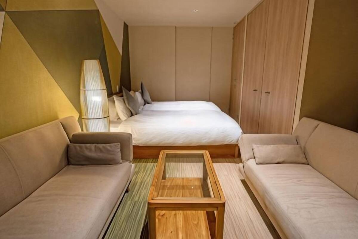 Ein modernes Hotelzimmer mit einem großen Bett, zwei Sofas, einem Holztisch und einer Lampe.