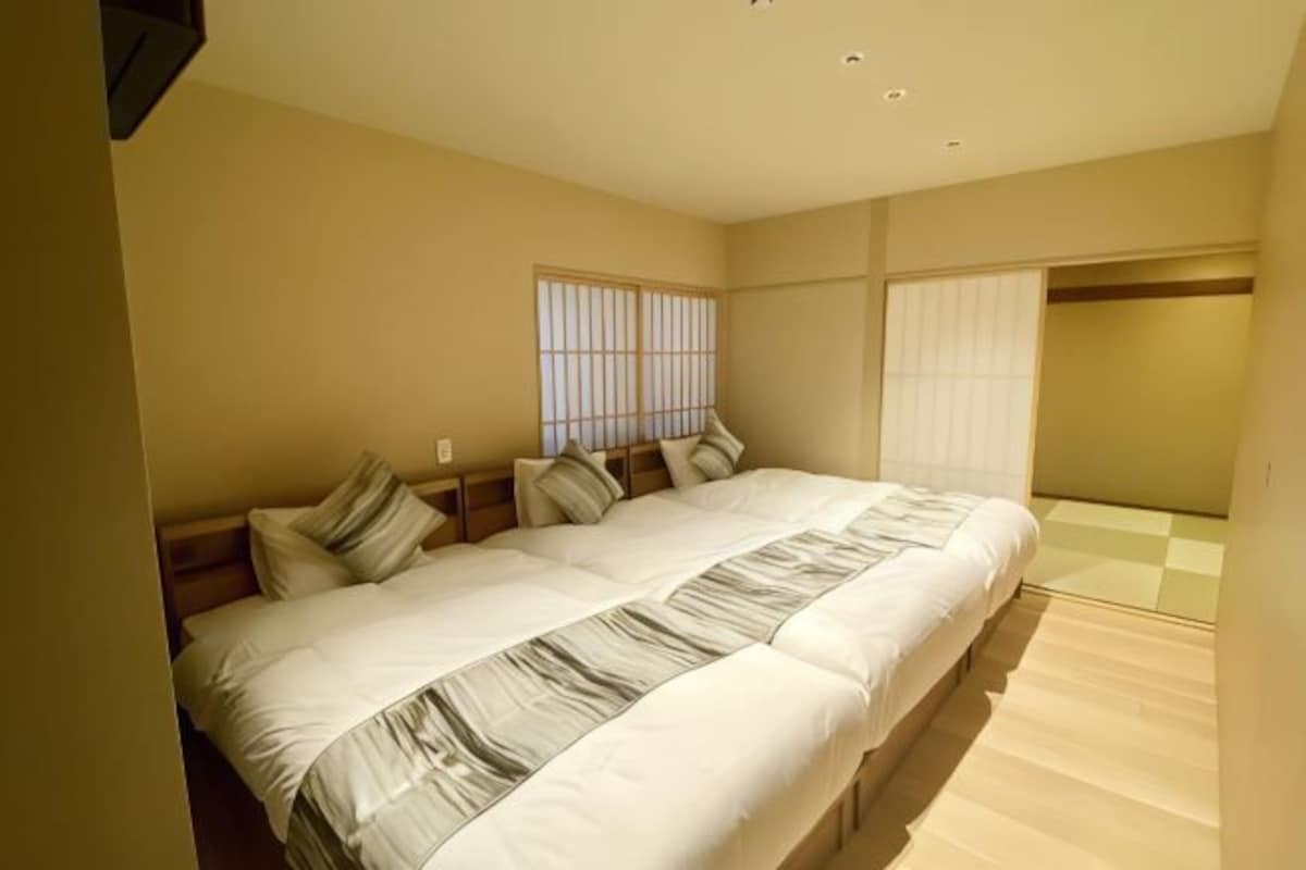 A bedroom with a large bed, a window with blinds, and a checkered floor.