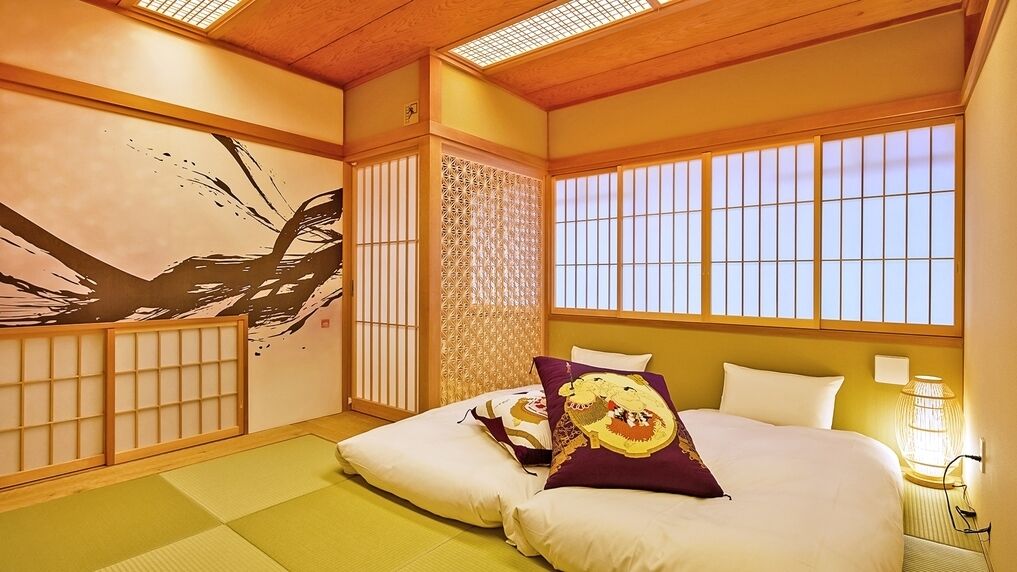 A traditional Japanese-style room with tatami flooring, shoji screens, and a large painting on the wall.