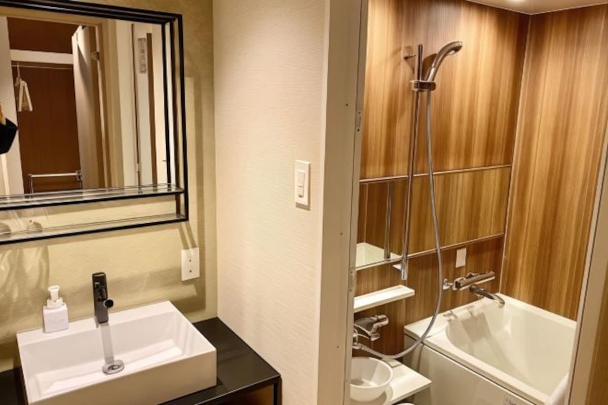 A bathroom with a white sink, mirror, and a wooden shower enclosure.