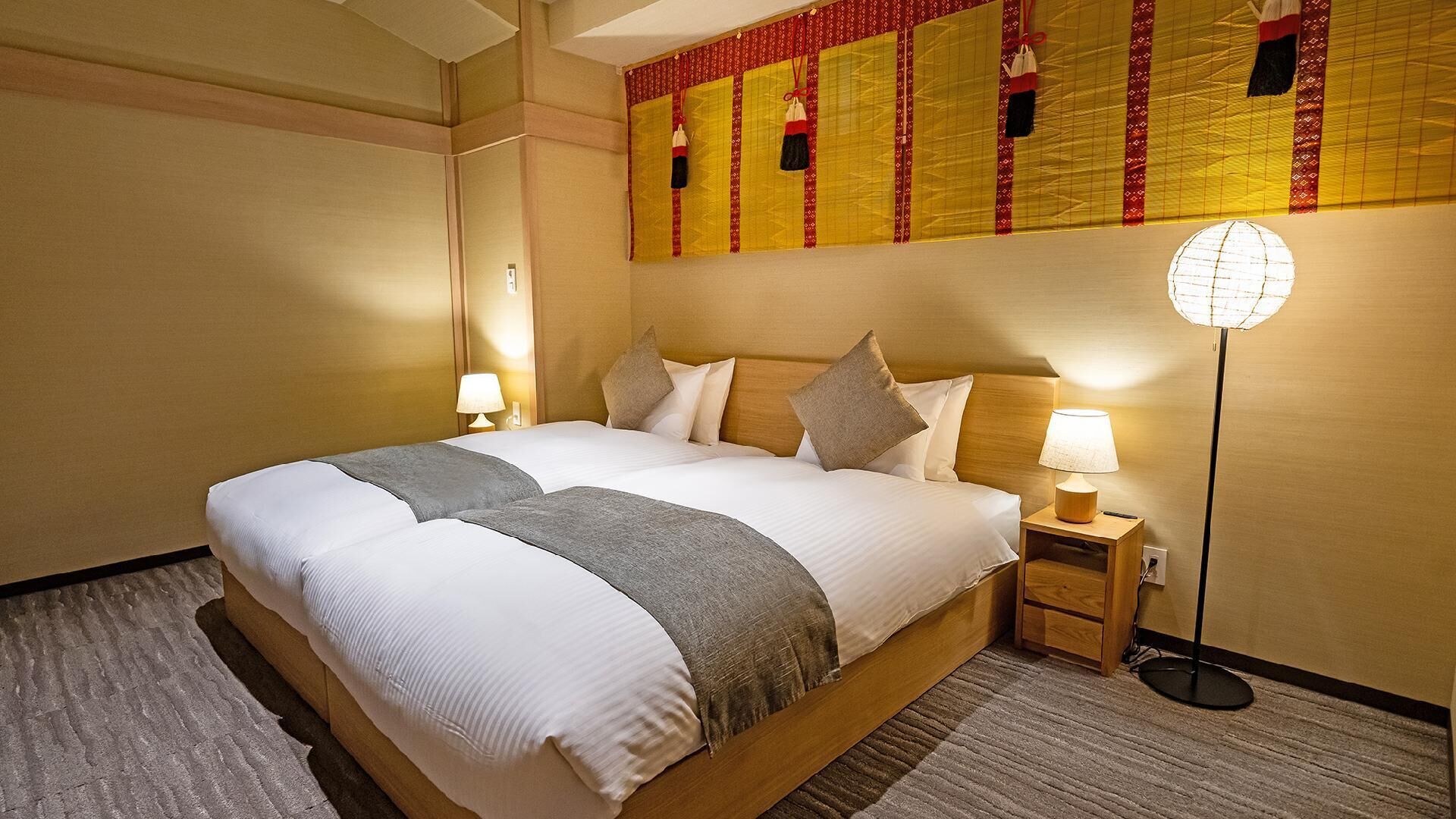 Une chambre d’hôtel avec un grand lit, des lampes de chevet, une lampe sur pied et un panneau décoratif mural.