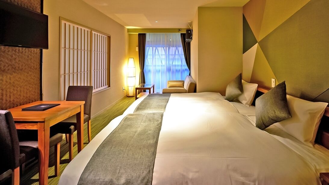 Une chambre d’hôtel avec un lit, un bureau, une chaise, une télévision et une fenêtre avec des rideaux.