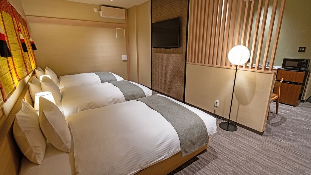 Une chambre d’hôtel avec deux lits, une télévision, un bureau et un four à micro-ondes.