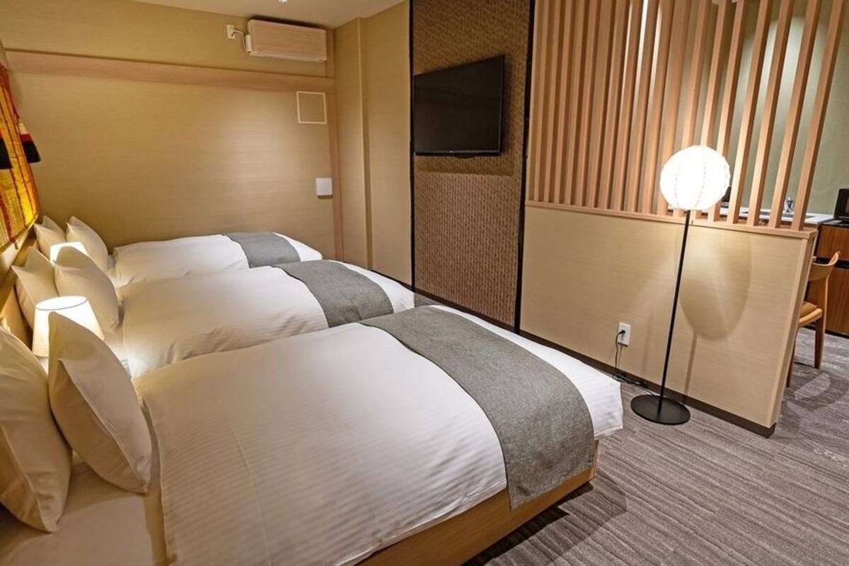 Ein Hotelzimmer mit zwei Betten, einem Fernseher, einem Schreibtisch und einer Mikrowelle.