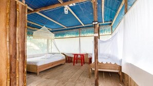 A room with a bed, a small table, and a mosquito net. - Red Uakari Jungle Lodge (Iquitos)
