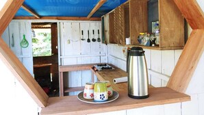 A small kitchen area with a wooden table, a kettle, and a plate with cups. - Red Uakari Jungle Lodge (Iquitos)
